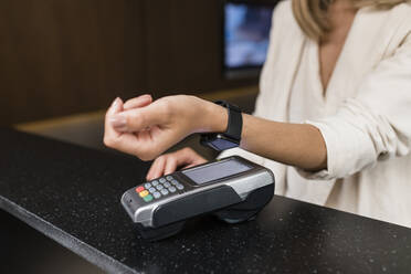 Hand of businesswoman making contactless payment through smart watch at restaurant - JRVF03128