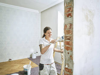 Happy painter painting doing final painting in apartment - CVF02020