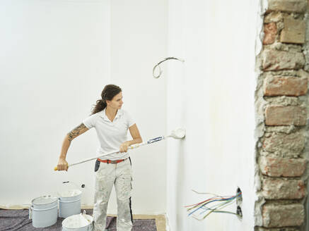 Painter with paint roller doing final painting in apartment - CVF02022