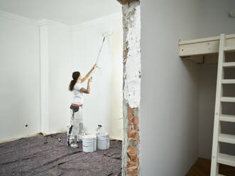 Painter doing final painting with paint roller in apartment - CVF02024