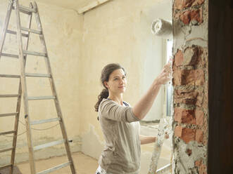 Maler, der mit einer Rolle auf eine Wand in einer Wohnung malt - CVF02028