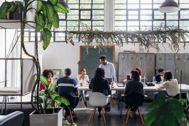 Geschäftsleute und Geschäftsfrauen diskutieren am Schreibtisch im Büro - MEUF06626