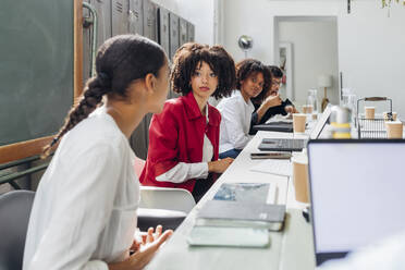 Multiracial friends looking at businesswoman talking in office meeting - MEUF06633