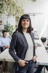 Confident businesswoman with hands in pockets at workplace - MEUF06655