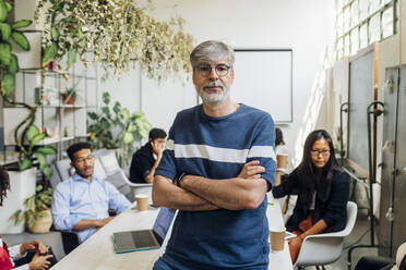 Businessman with arms crossed at desk in office - MEUF06658