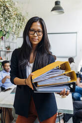 Businesswoman with eyeglasses holding files in coworking office - MEUF06665