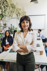 Confident businesswoman with arms crossed at coworking office - MEUF06671