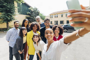 Smiling businesswoman taking selfie with multiracial business colleagues - MEUF06690