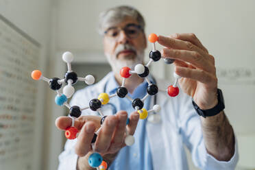 Mature scientist holding helix model in laboratory - MEUF06705