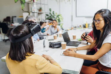 Businesswoman with virtual reality simulator by colleagues in office - MEUF06717