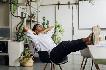 Young businessman relaxing on chair at office - MEUF06755