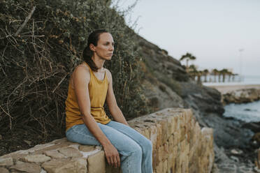 Sad woman sitting on wall - DMGF00774