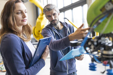 Technicians discussing technical solutions looking at industrial robot - WESTF24815