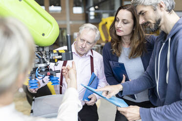 Technicians showing new industrial robot to senior colleague - WESTF24820