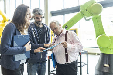 Technicians showing new industrial robot to senior colleague - WESTF24823