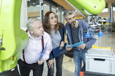 Technicians showing new industrial robot to senior colleague - WESTF24826