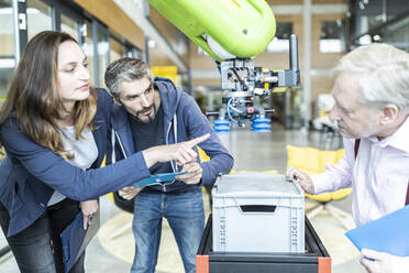 Technicians showing new industrial robot to senior colleague - WESTF24828