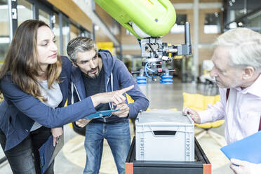 Techniker zeigen einem älteren Kollegen einen neuen Industrieroboter - WESTF24828