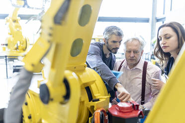 Technicians examining industrial robot in factory - WESTF24839