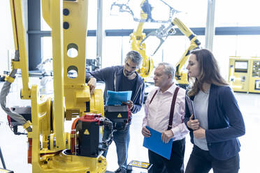 Technicians examining industrial robot in factory - WESTF24840