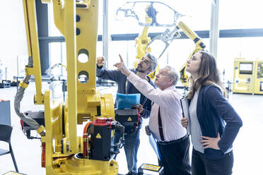 Technicians examining industrial robot in factory - WESTF24841