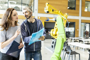 Technicians having meeting in front of industrial robot - WESTF24845