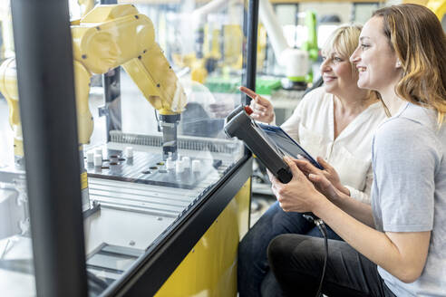 Women in factory using control of industrial robot - WESTF24886