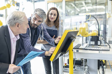 Technicians in industrail factory explaining control panel to senior manager - WESTF24890