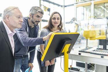 Technicians in industrail factory explaining control panel to senior manager - WESTF24891