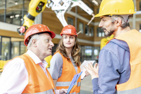 Senior colleague in work wear having meeting with skilled workers - WESTF24896