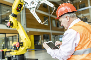 Facharbeiter steuert Roboterarm mit digitalem Tablet - WESTF24899