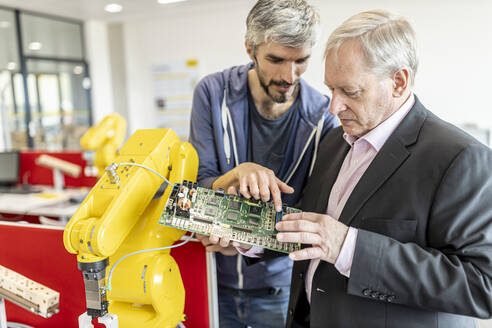 Engineer explaining new robot motherboard to supervisor - WESTF24963