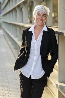 Smiling mature businesswoman leaning on railing - AGOF00291
