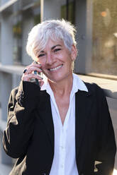 Smiling businesswoman talking on smart phone - AGOF00296