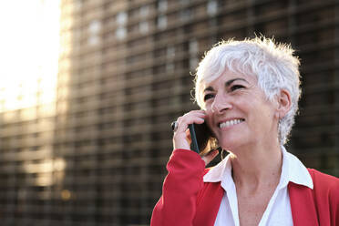 Glückliche Geschäftsfrau mit weißem Haar, die mit einem Smartphone telefoniert - AGOF00298