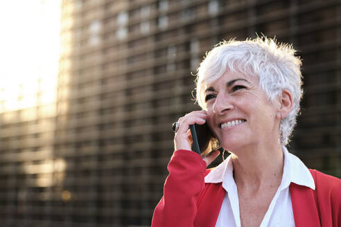 Happy businesswoman with white hair talking on smart phone - AGOF00298