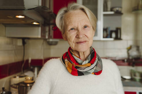 Lächelnde ältere Frau mit kurzen weißen Haaren in der Küche - OSF00193