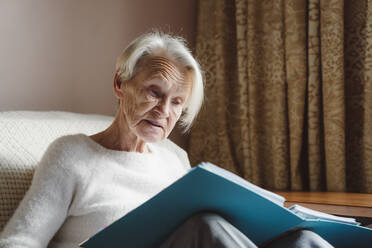 Senior woman with white hair reading document - OSF00198