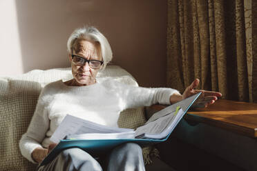 Ältere Frau mit Brille beim Lesen von Dokumenten zu Hause - OSF00201