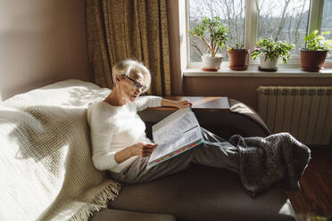 Frau mit Brille beim Lesen von Dokumenten zu Hause - OSF00205