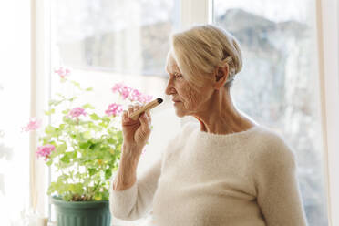 Ältere Frau riecht zu Hause am Palo-Santo-Stab - OSF00221