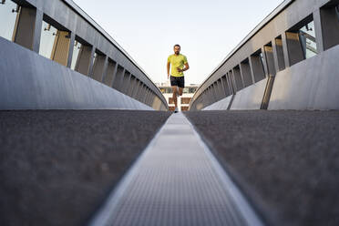 Junger Mann joggt auf einer Fußgängerbrücke - DIGF18189