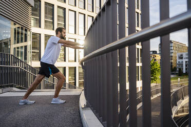 Young man doing warm up exercise on footbridge - DIGF18201