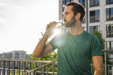 Junger Mann trinkt Wasser an einem sonnigen Tag - DIGF18208