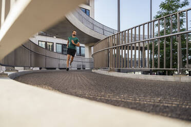 Junger Mann joggt auf erhöhtem Gehweg - DIGF18214