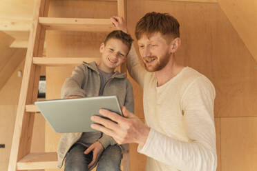 Vater und Sohn verwenden Tablet-PC für die Gestaltung der Inneneinrichtung in einem Öko-Holzhaus - OSF00240