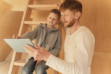 Vater und Sohn verwenden Tablet-PC für die Gestaltung der Inneneinrichtung in einem Öko-Holzhaus - OSF00241