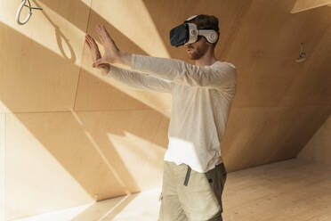 Ein Mann benutzt eine 3D-Brille, um die Inneneinrichtung eines Öko-Holzhauses zu visualisieren - OSF00246