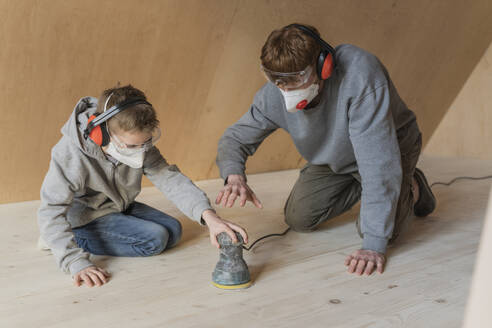 Vater und Sohn schleifen den Boden in ihrem neuen Ökohaus - OSF00259