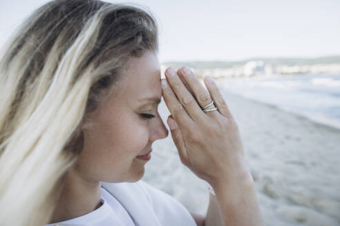 Glückliche Frau mit verschränkten Händen am Strand stehend - SIF00236